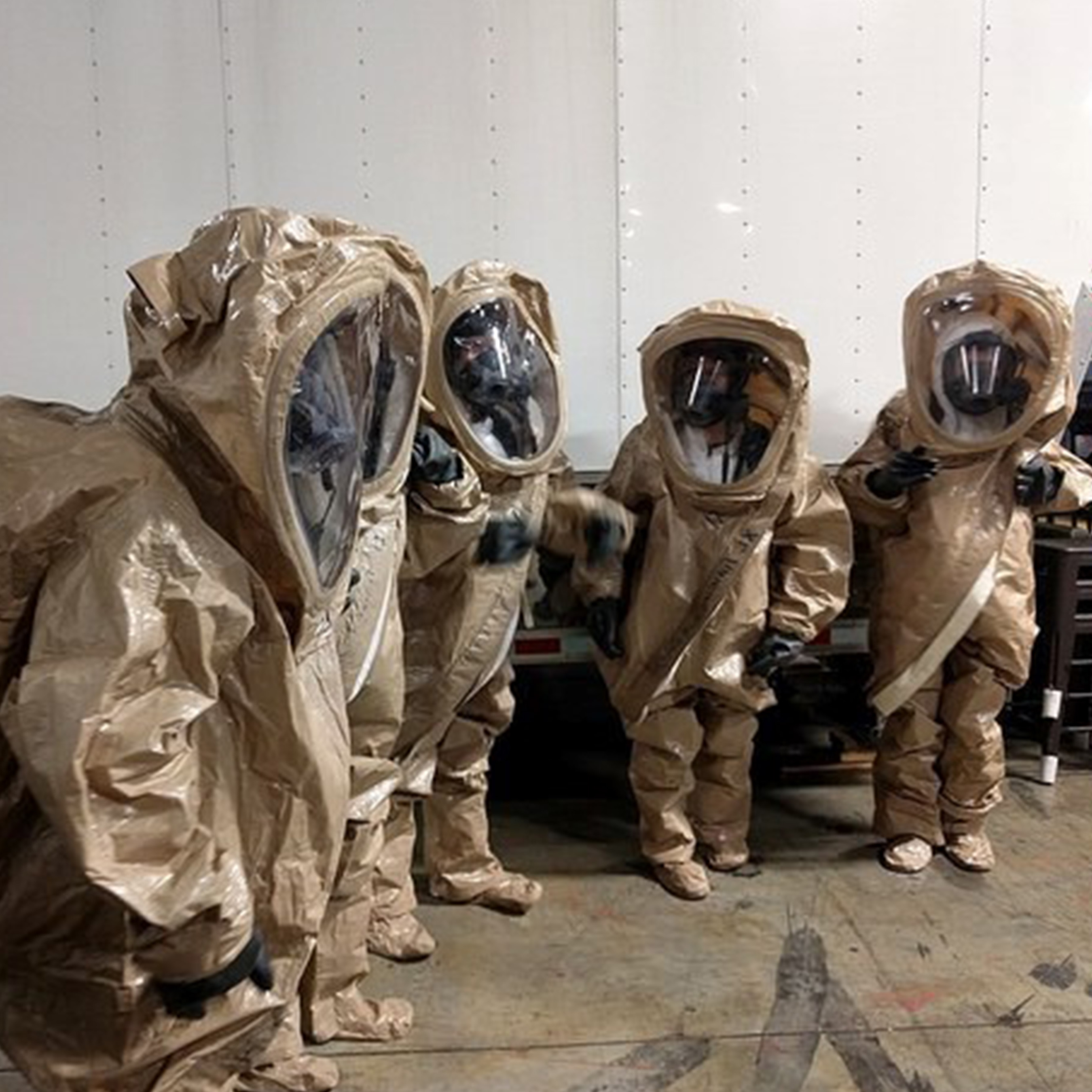 Four CDC Interns are dressed in beige hazard-material suits.