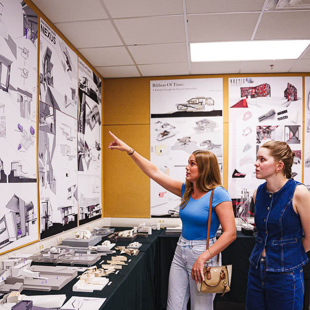 A student points up at her work hanging on the wall during and SACD open house event.