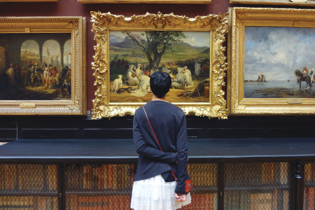 Art history student looking at artwork in a museum.