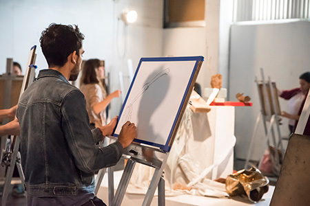 Students in the drawing studio drawing at their easels.