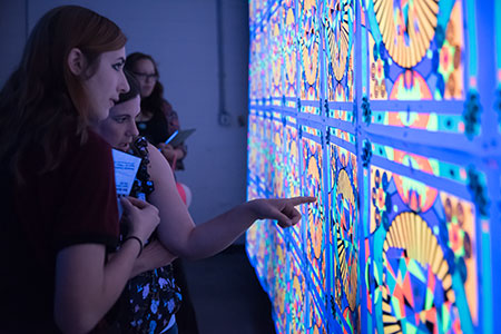 Visiting students checking out the print studio under blacklight during USF ArtHouse.