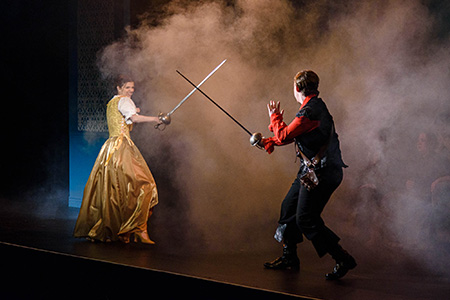 a man and woman on stage sword fighting