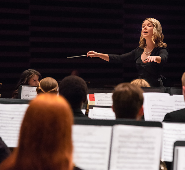 Orchestra referencing standing conductor during a performance.