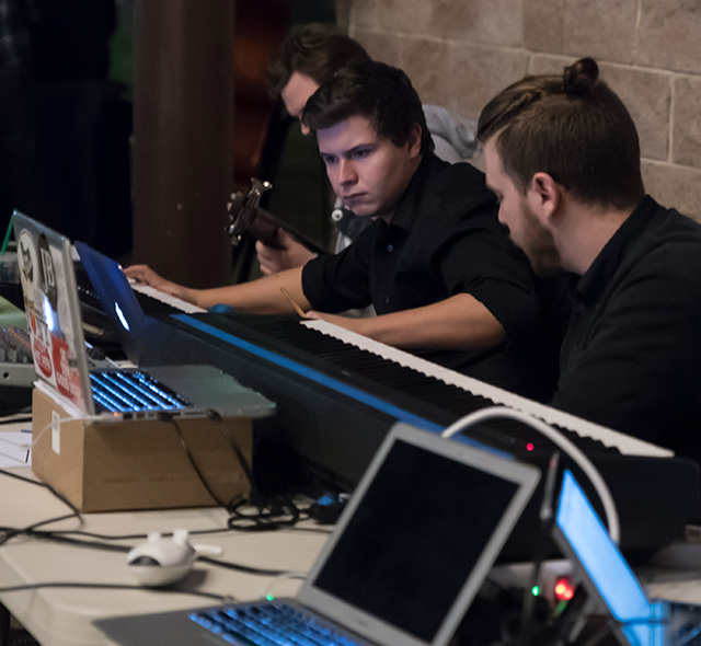 Electronic music students setting up during a performance of their new compositions.