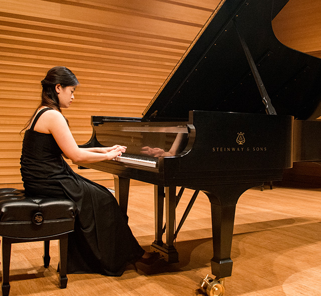 Music student playing during piano performance.