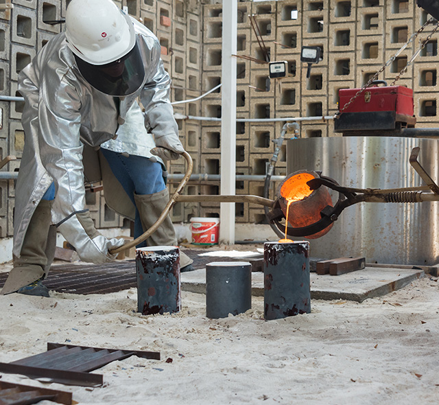 Students pouring molten bronze into a mold. 