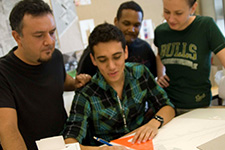 A faculty member helping three architecture students on a paper sketch project.