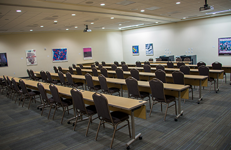 Conference center tables and chairs assembled to face front of room.