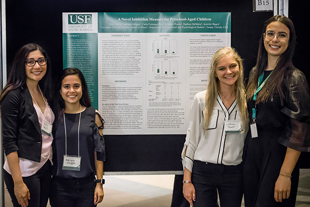 Daisy Solis, Adriana Melgan, Lindsay Power, and Carla Formoso Pico pose for a photo in front of their research poster titled "A Novel Inhibition Measure for Preschool Children” at the 2018 USF Undergraduate Research Symposium