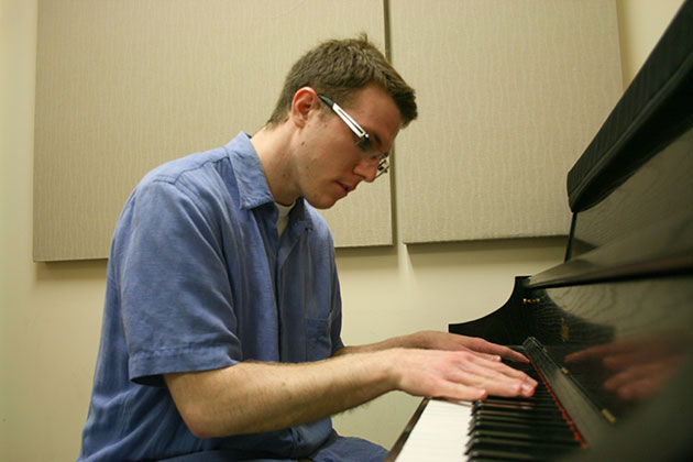 Zachary Bornheimer plays piano in a practice room in the School of Music