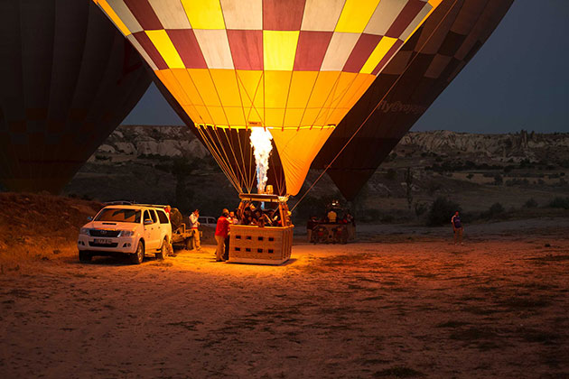 Photo of a hot air balloon with people in it next to a white suv