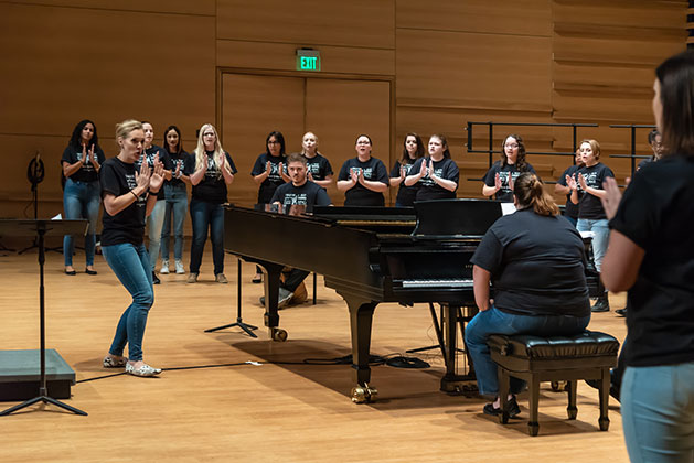 Ruthie Nelson claps with the HCC Concert Chorus as she directs the ensemble on stage of the USF Music Concert Hall