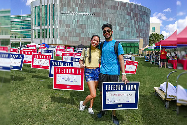 USF students Jordan Sparks and Dylan Bheem stand next to their signs in front of the Marshall Student Center