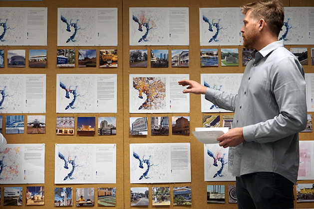 Architecture student Austin Jenquine stands in front of maps showing vulnerabilities in Hillsborough County