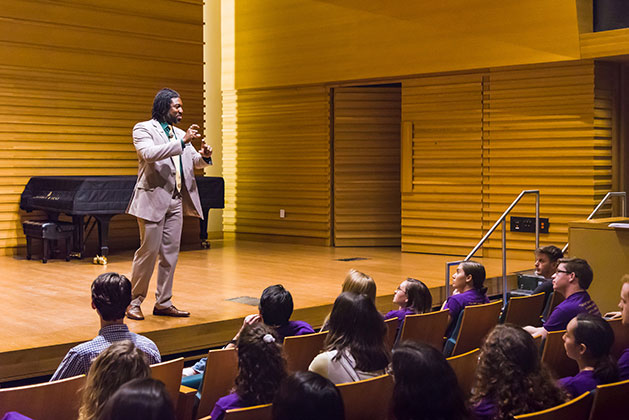 Dr. Dakeyan Graham stands on stage of Barness Recital hall before USF music students