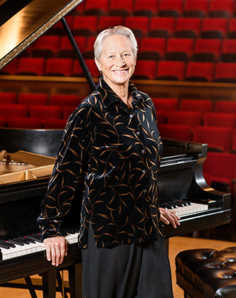 Rebecca Penneys in front of a piano in a concert hall