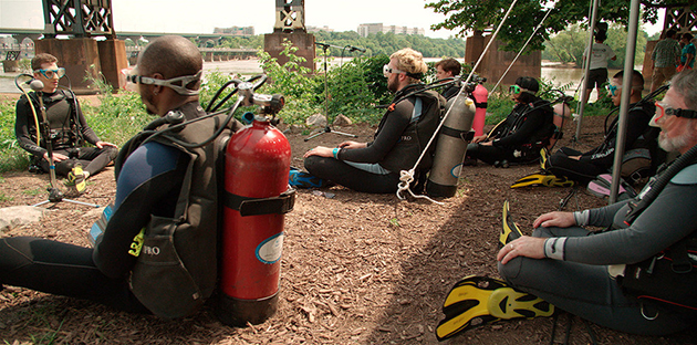 suba divers sit on the ground outdoors