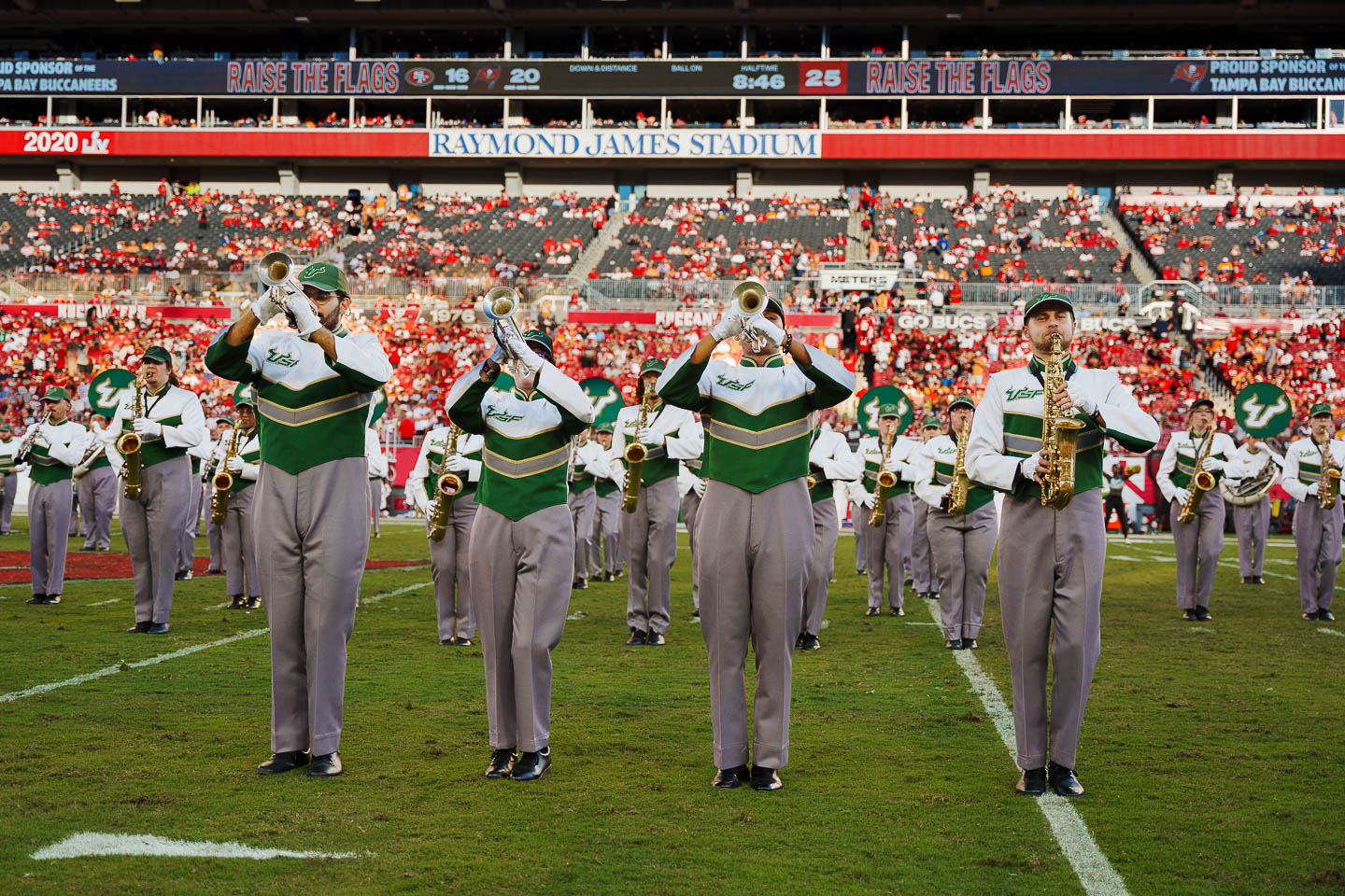 Trumpetists and saxophonist play on the field at Raymond James Stadium.