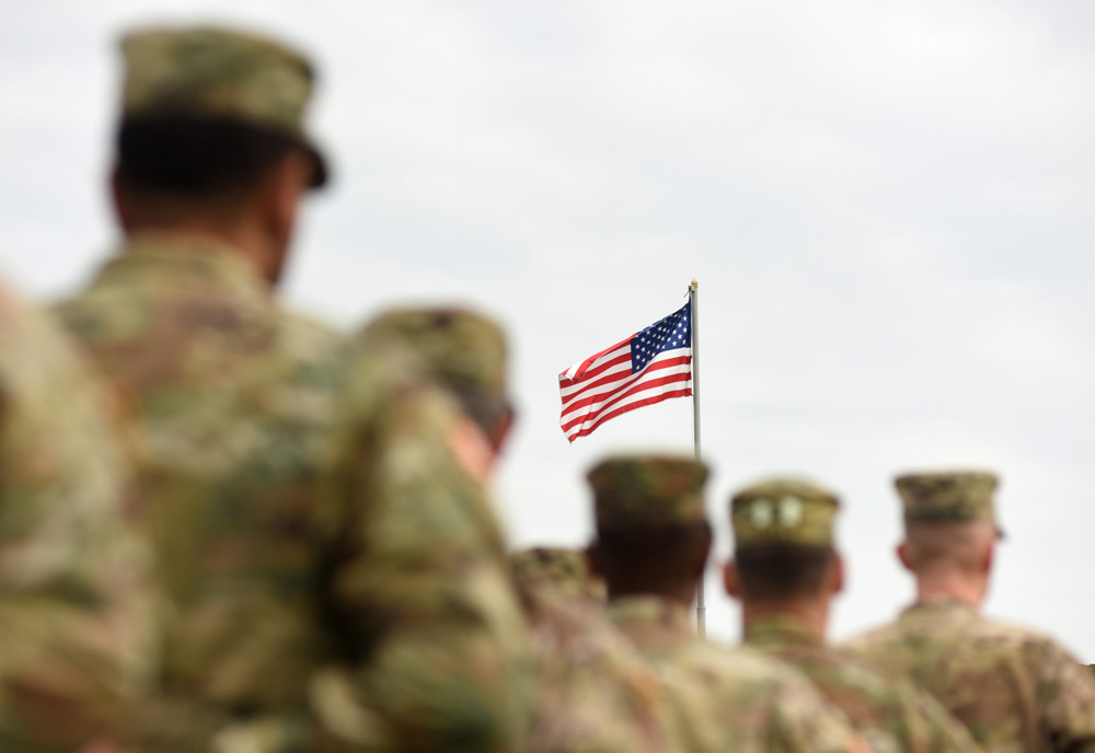 soldiers in camouflage military uniform, with US flag in the background
