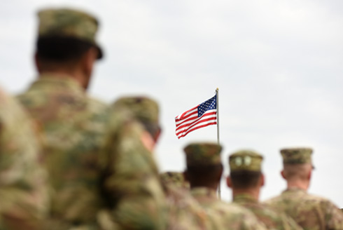 soldiers in camouflage military uniform, with US flag in the background