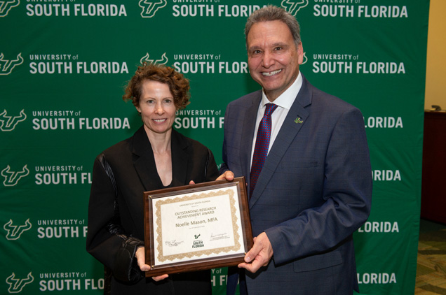 Professor Noelle Mason receiving an award from President Moez Limayem