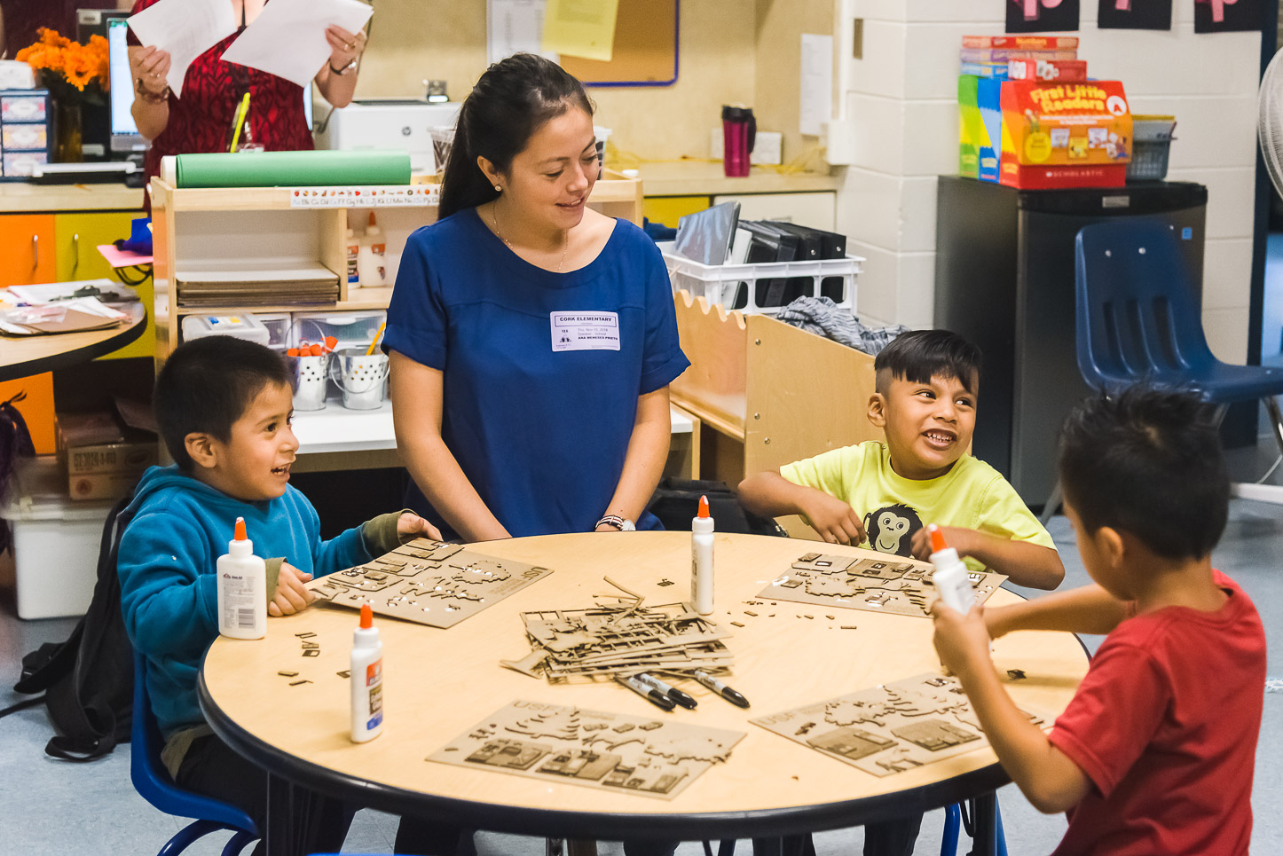 USF architecture student Ana Meneses sits at a table with three VPK students as they build model houses.