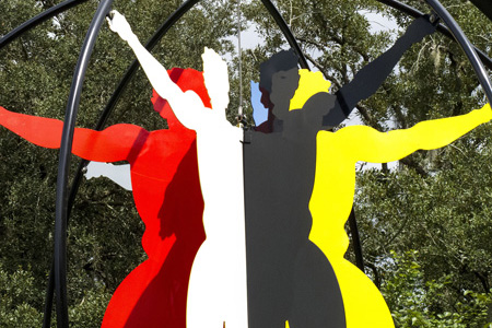 metal sculpture with human figures in red, white, black, and yellow