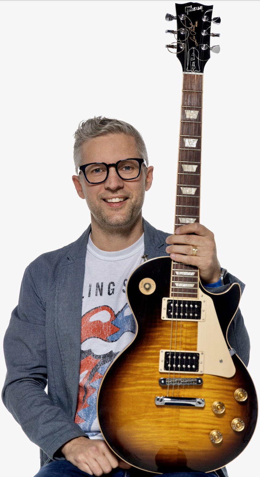 Clint Randles sitting while holding a guitar