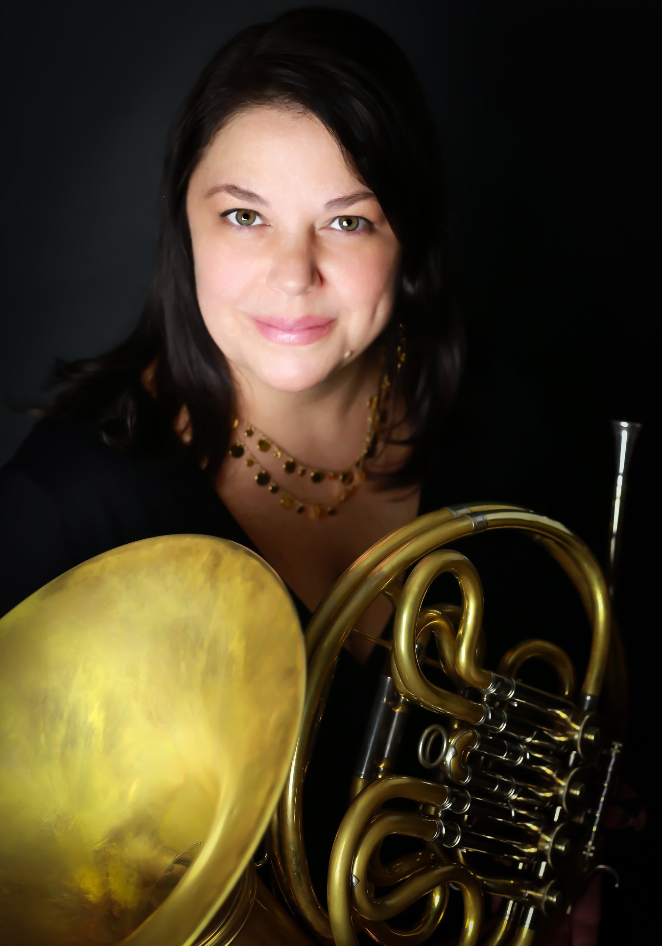 Lyndsie Wilson wearing a black top and holding a french horn