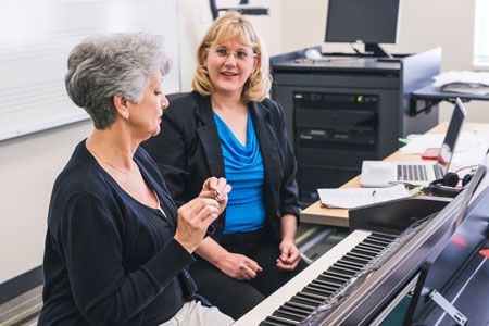 Dr. Jennifer Bugos working with a woman in the keyboard lab.