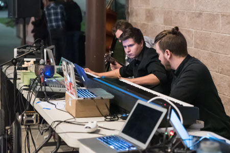 SYCOM students make audio adjustments on a laptop.