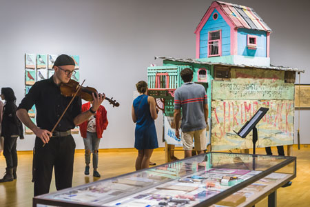 A SYCOM student performs with a violin in the Contemporary Art Museum.