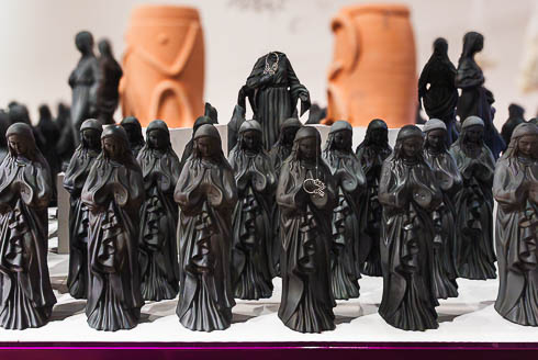 A line of black Virgin of Guadalupe statues, part of a piece by Adrian Gomez, titled Bisagras, 2025