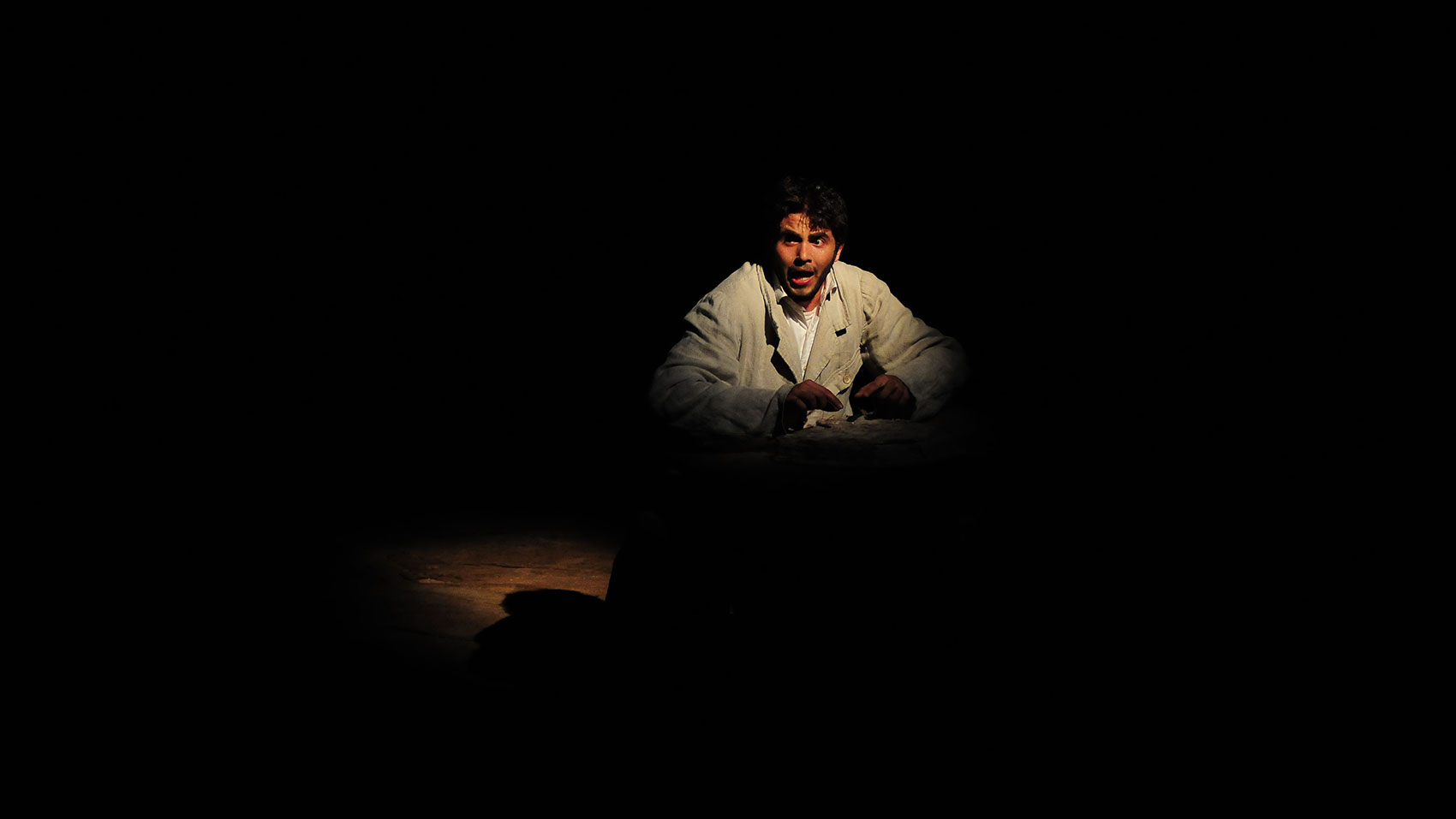 A man sitting down in the spotlight, speaking