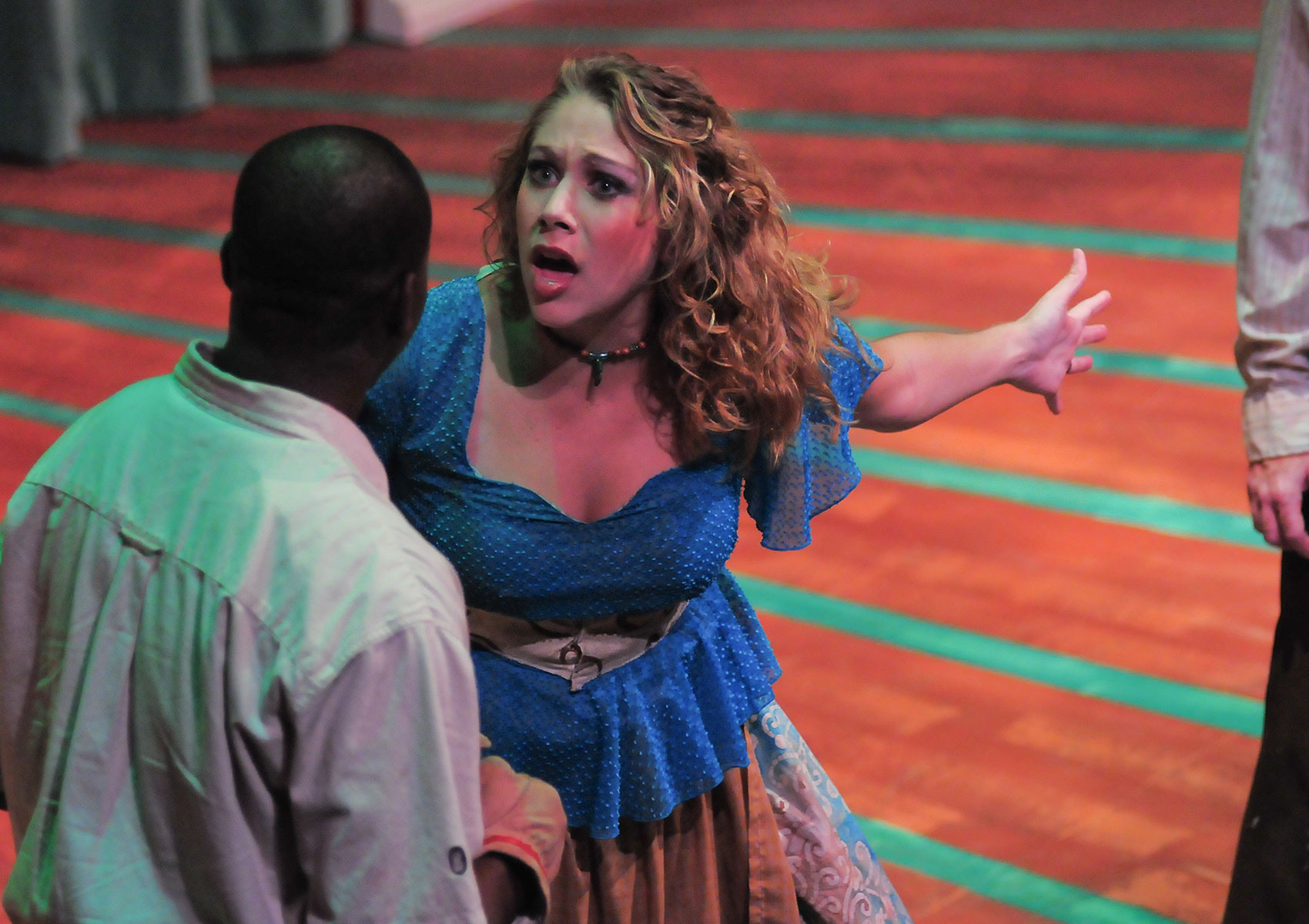 A distressed woman gestures behind her with an open hand while talking to a man.