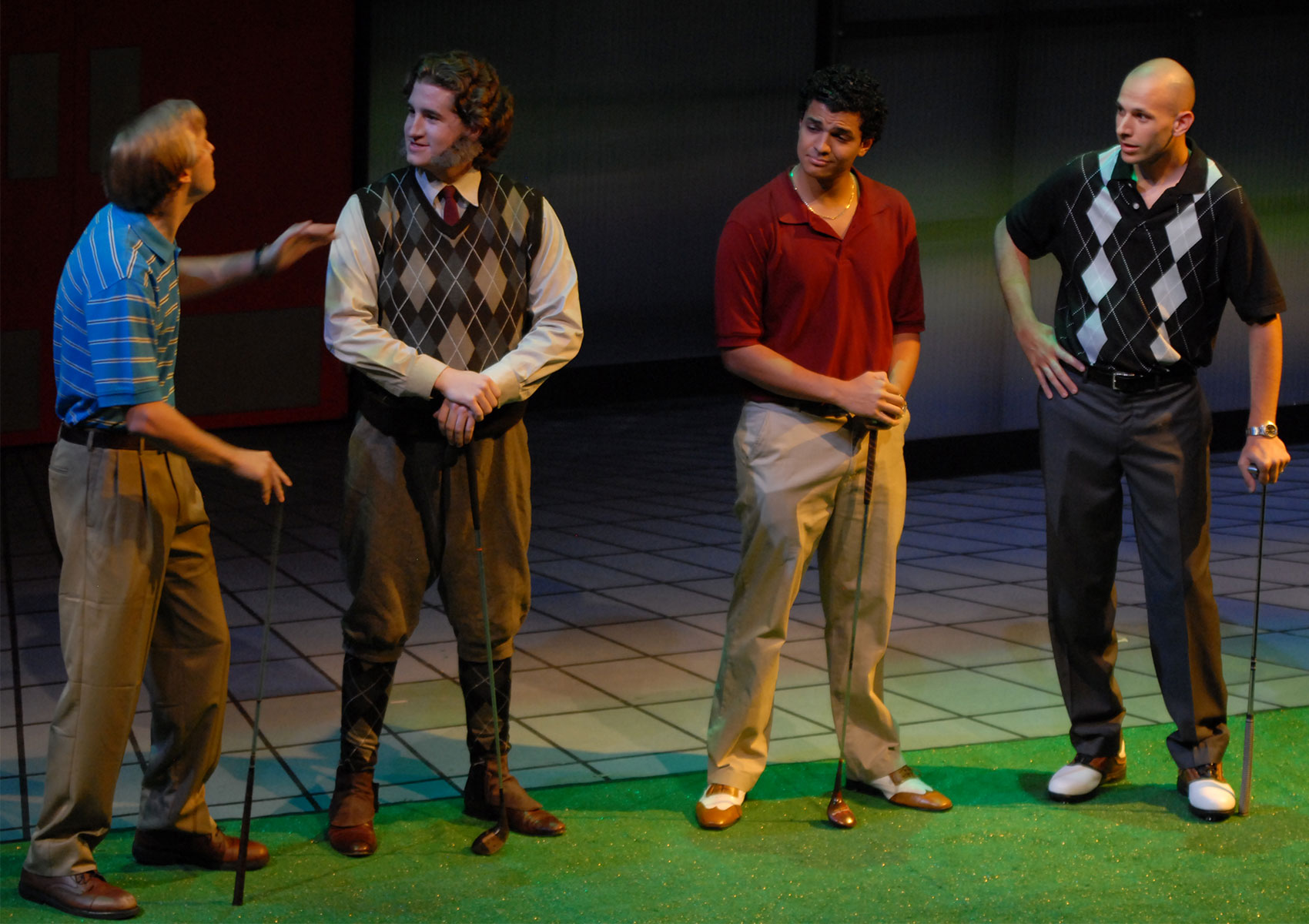 Four characters stand with clubs on a golf green, one at the far left is talking while the others listen.