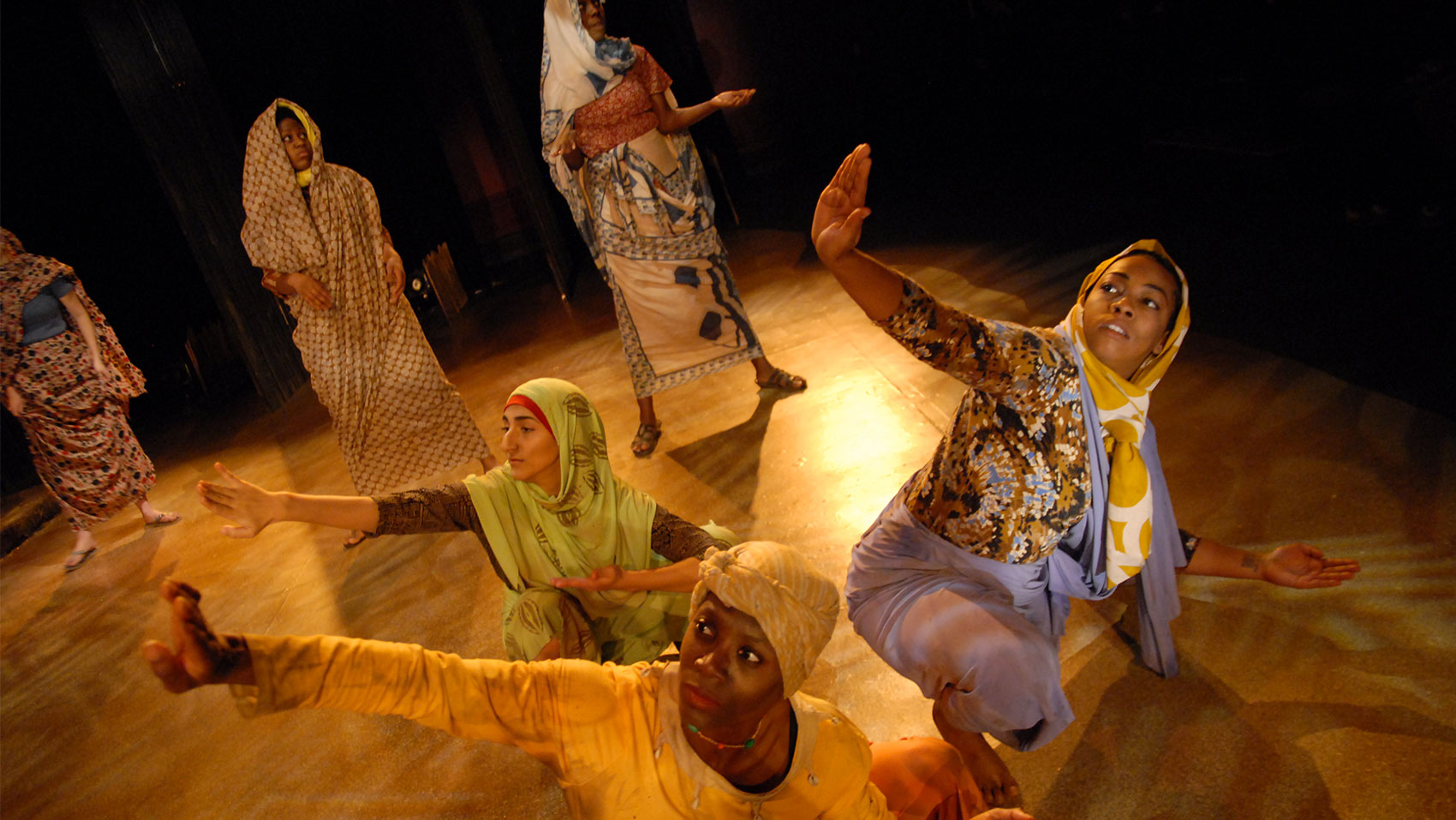 Women crouching on the floor with an arm stretched upwards