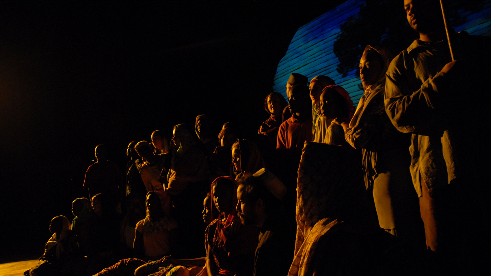 A group of people in the shadows looking at a point off stage