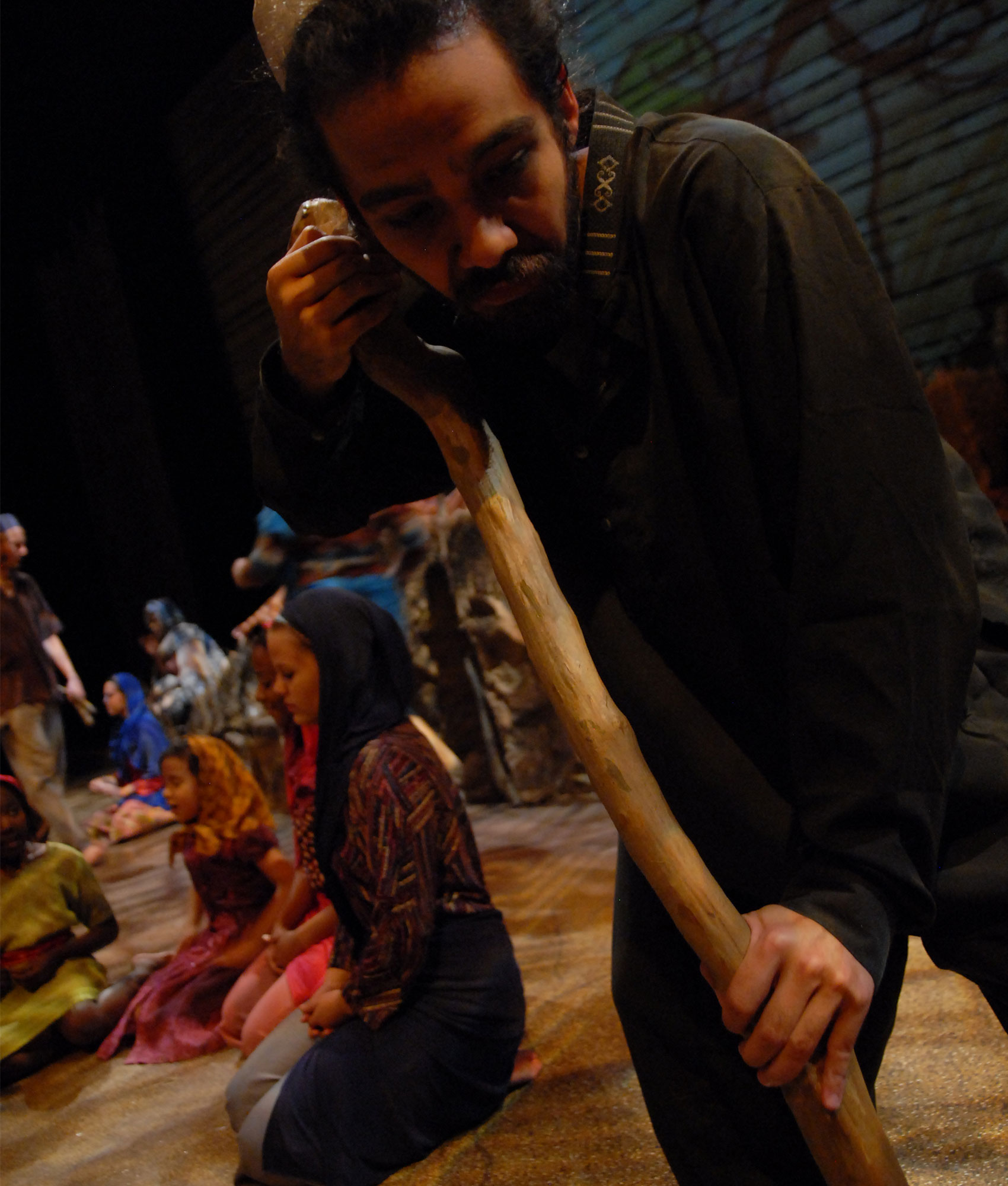 A man holds a stick and looks down at the ground