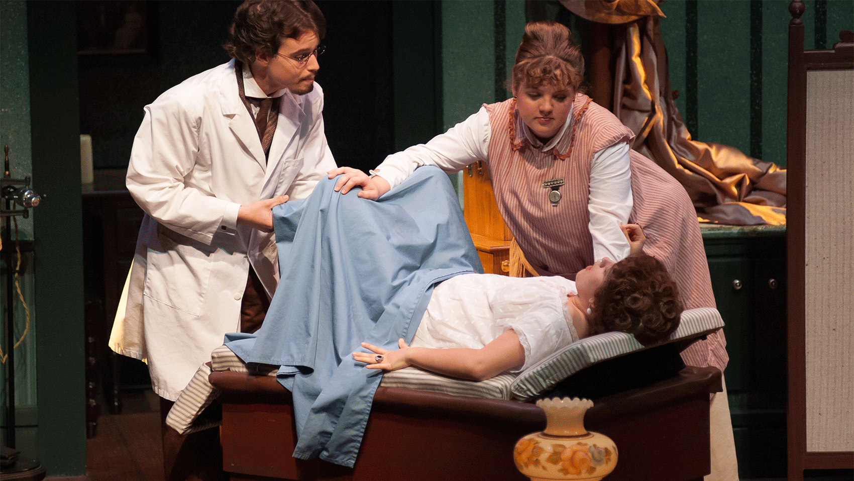 A woman laying down on a medical bed while a doctor and nurse attend to her