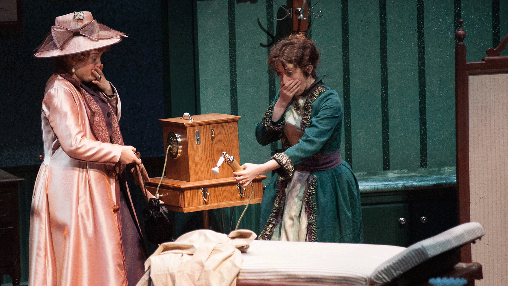 Two women looking down at a telephone in shock