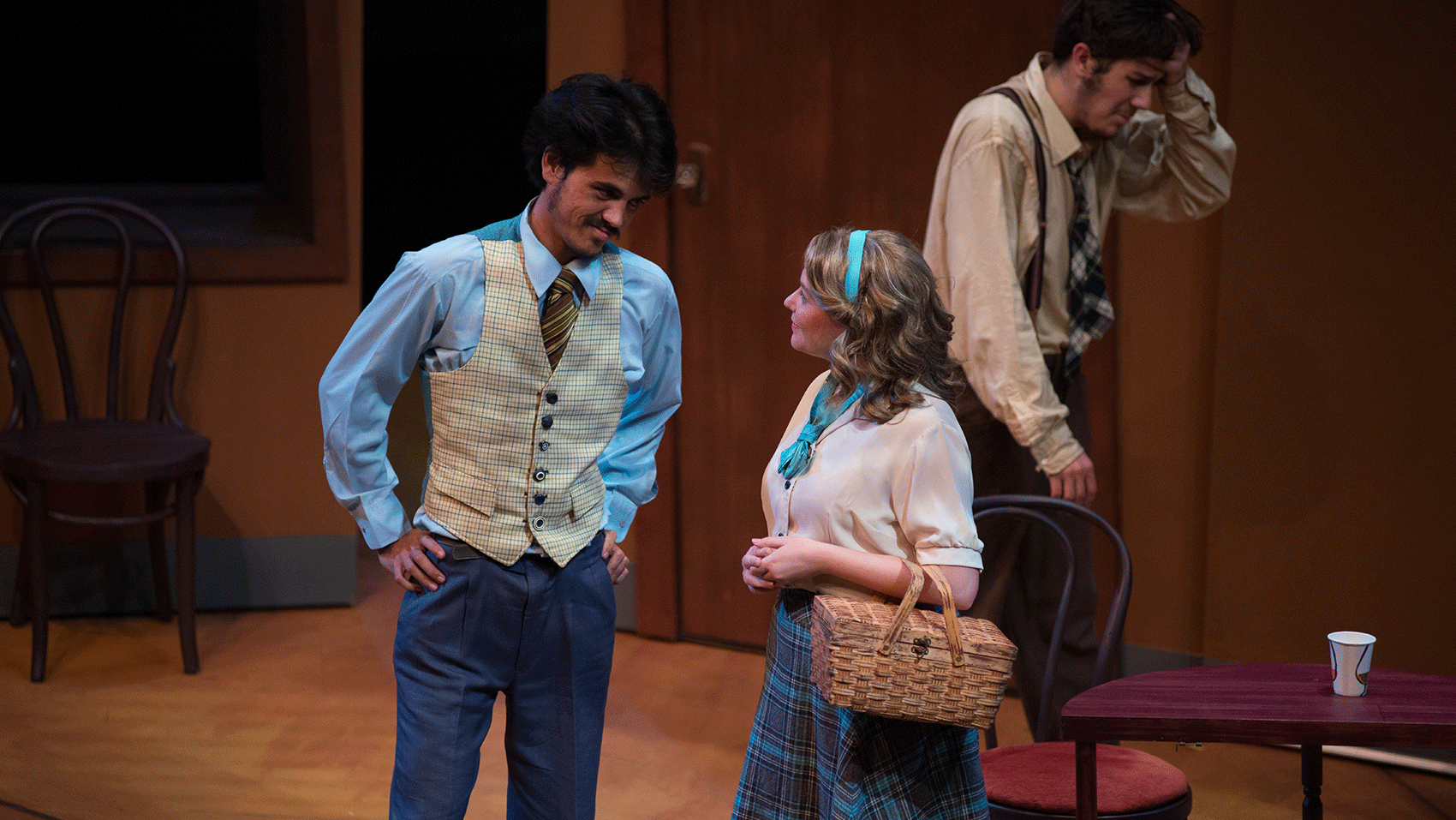 A woman and man talking and smiling while another man is distraught in the background