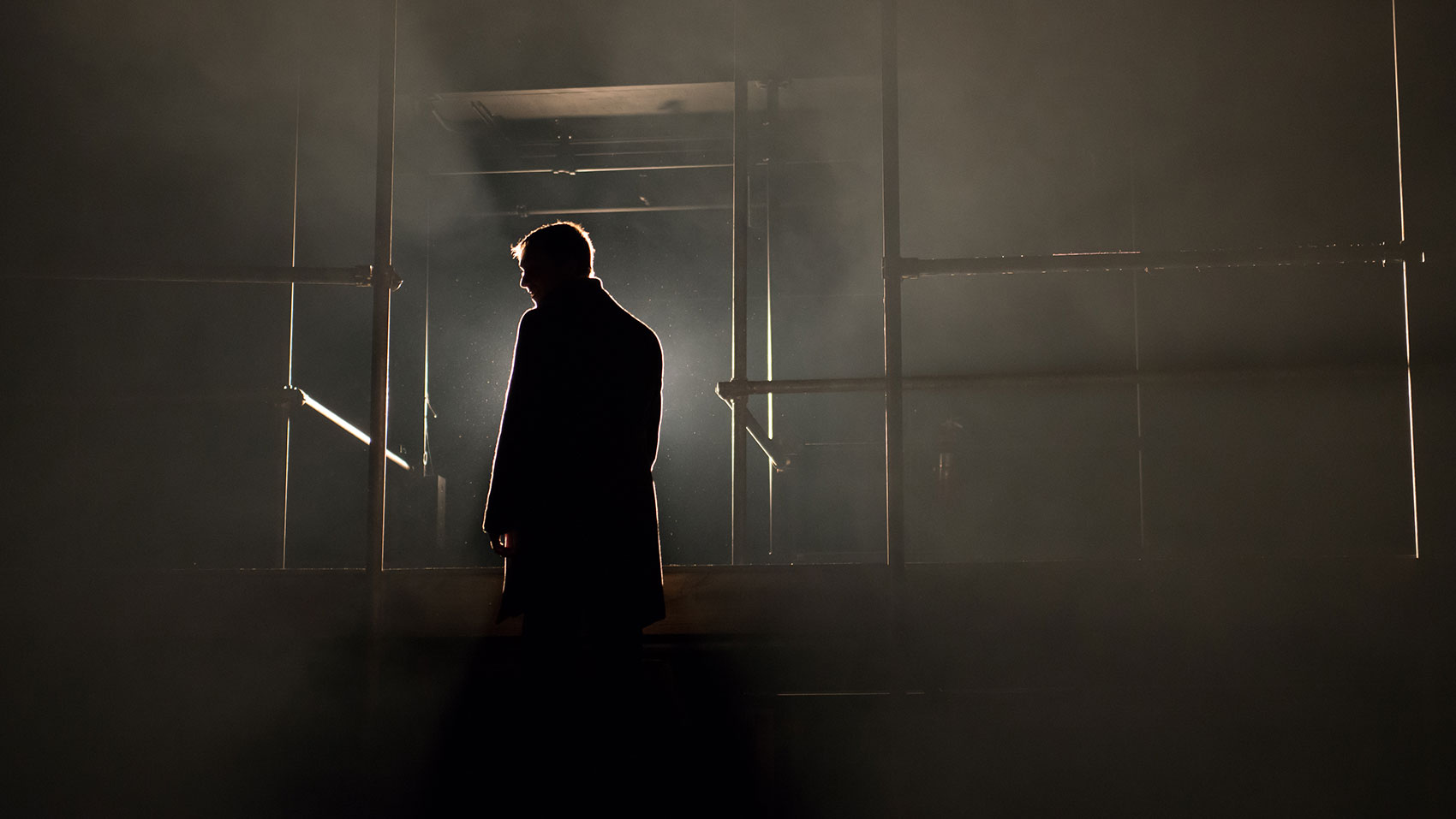 A man stands silhouetted against a bright light. 
