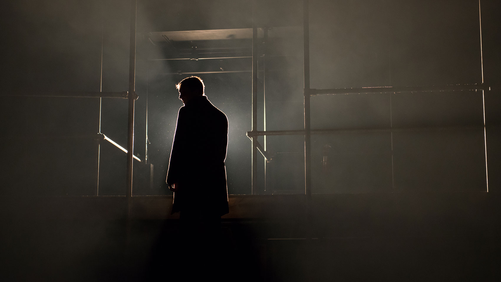 A man stands silhouetted against a bright light.