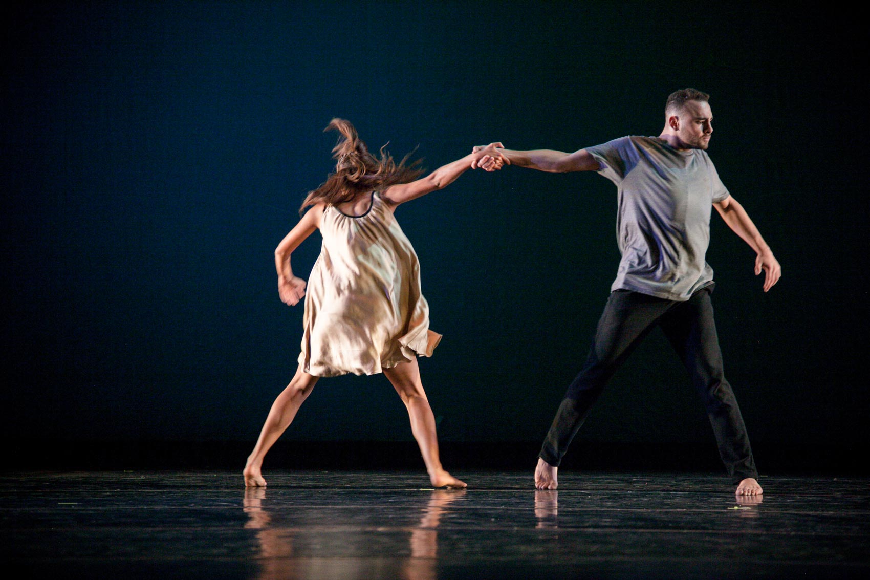 Two dancers use each other's body weight to hold each other up.