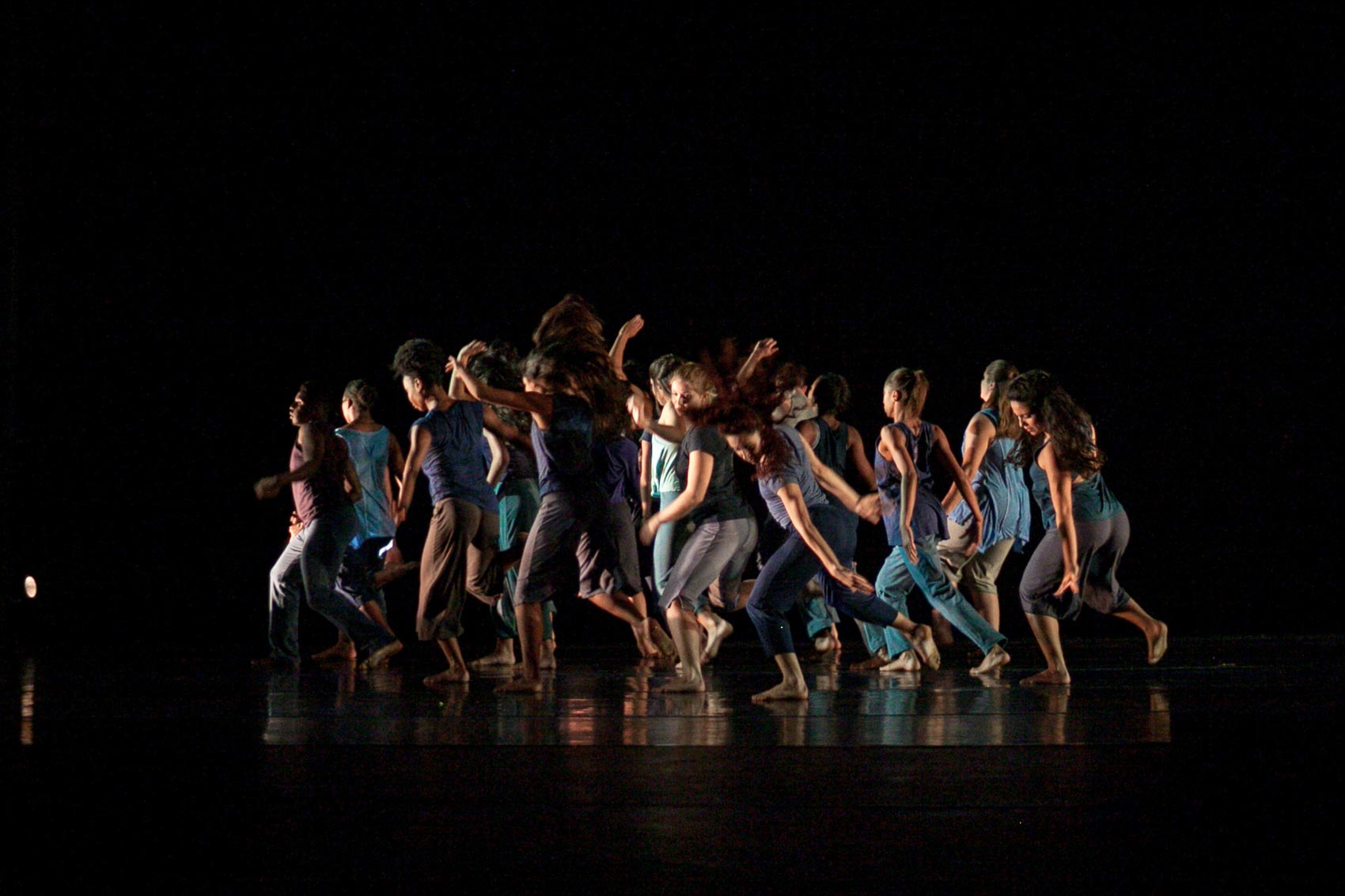 A large group of dancers move together on stage.
