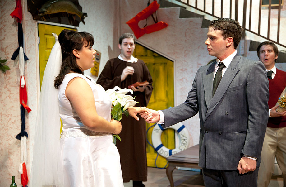 Two characters look on in shock while a man in a suit holds the hand of a woman in a wedding dress holding flowers, who also appears shocked.