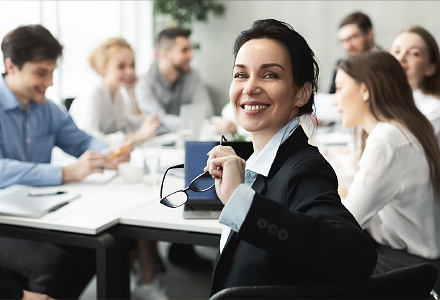 Person turning to camera while sitting at conference table with others