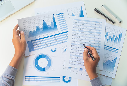 person's hands holding several sheets of graphs and data