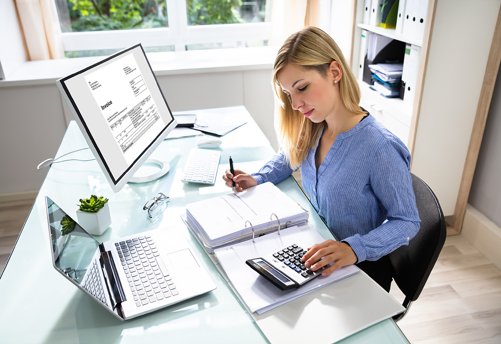 Person working at a desk with laptop and binder of papers